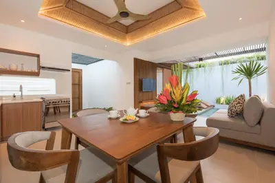 a dining room and living room with a wooden table and chairs at Fenosa Seminyak Villas in Seminyak