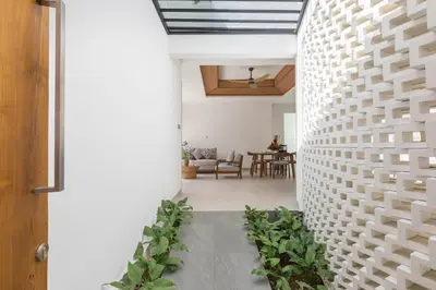 a hallway with a white brick wall with plants at Fenosa Seminyak Villas in Seminyak