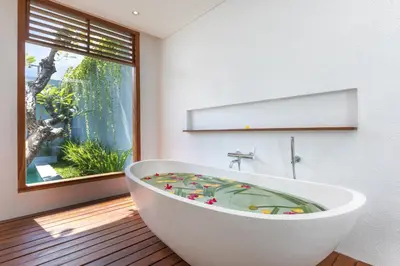 a bath tub in a bathroom with a window at Fenosa Seminyak Villas in Seminyak