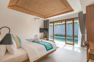a bedroom with a bed and a view of a pool at Fenosa Seminyak Villas in Seminyak
