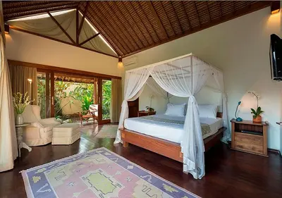 a bedroom with a canopy bed and a living room at Villa Andalas in Seminyak
