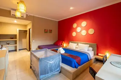 a bedroom with two beds and a red wall at Jepun BnB Bali in Seminyak