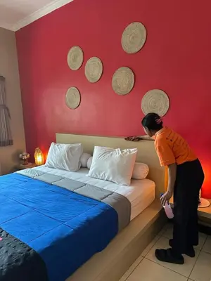a woman standing next to a bed in a bedroom at Jepun BnB Bali in Seminyak