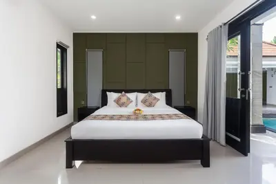 a bedroom with a large bed with white sheets at Maja Villa Batubelig by GenuineHost in Canggu