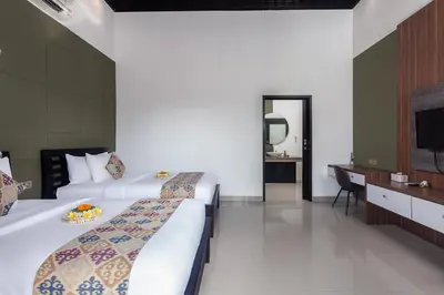 a hotel room with two beds and a television at Maja Villa Batubelig by GenuineHost in Canggu