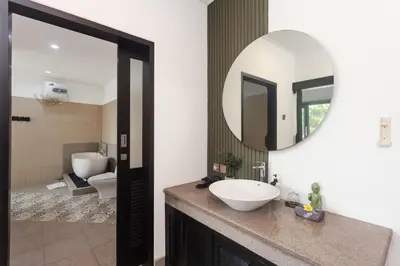 a bathroom with a sink and a mirror at Maja Villa Batubelig by GenuineHost in Canggu