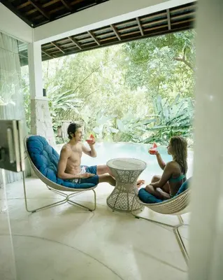 a man and a woman sitting in chairs on a patio at Umani Village in Kerobokan