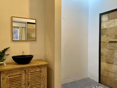 a bathroom with a black bowl sink on a wooden vanity at VILLA LUNA in Kerobokan