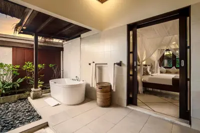 a bathroom with a bath tub and a bedroom at Villa Gading by Alfred in Bali in Seminyak