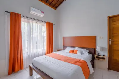 a bedroom with a bed with orange curtains and a window at Villa Padma by Best Deals Asia Hospitality in Nusa Dua