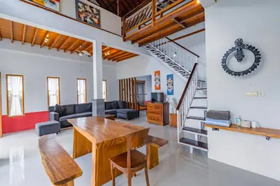 a living room with a wooden table and a staircase at Villa Padma by Best Deals Asia Hospitality in Nusa Dua