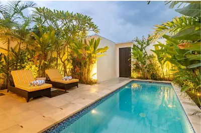 a swimming pool with two chairs next to a house at Villa Caorrun Canggu in Canggu