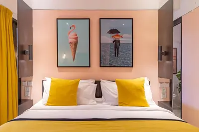 a bedroom with a bed with yellow pillows and framed pictures at Villa Caorrun Canggu in Canggu