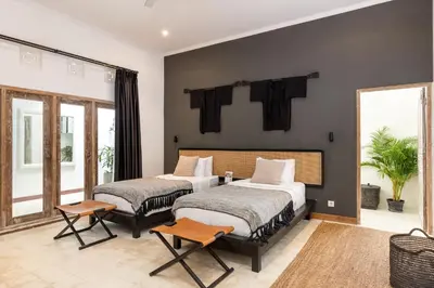 two beds in a room with black walls at Villa Gauguin by Villa Finder in Seminyak