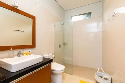 a bathroom with a sink and a glass shower at Villa Kamboja Premium walk to double six Beach - enclosed living room with AC in Seminyak