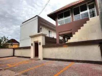 a large white building with a staircase in a parking lot at Gaing Mas Residence By Gaing Mas Group in Jimbaran