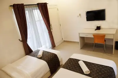 a hotel room with two beds and a desk and a television at Gaing Mas Residence By Gaing Mas Group in Jimbaran