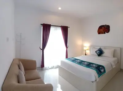 a bedroom with a bed and a chair and a window at Gaing Mas Residence By Gaing Mas Group in Jimbaran
