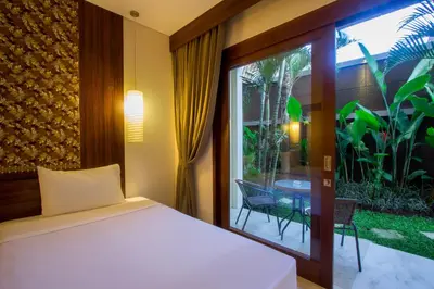 a bedroom with a bed and a balcony with a table at M Suite Bali in Seminyak
