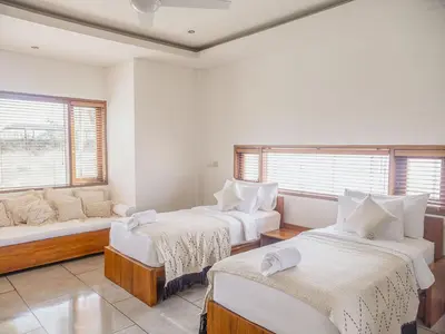 a room with two beds and a couch and windows at AB Villa & Apartments in Seminyak