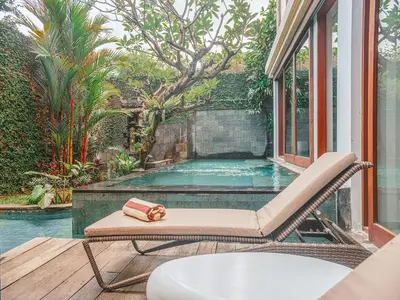 a chair on a deck with a swimming pool at AB Villa & Apartments in Seminyak