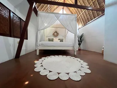 a bedroom with a bed with a canopy and a rug at Tiga Pantai Villa Legian in Legian