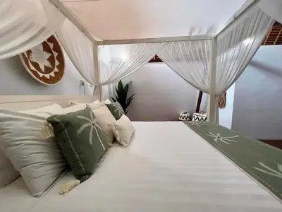 a bedroom with a white bed with green and white pillows at Tiga Pantai Villa Legian in Legian
