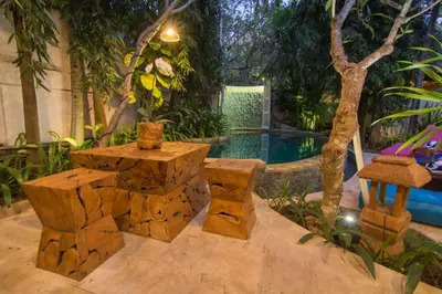 a patio with a table and benches and a pool at Bale Seminyak in Seminyak