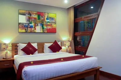 a bedroom with a large bed and a painting on the wall at Delu Villas & Suite in Kerobokan