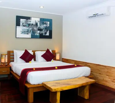 a bedroom with a large bed and a wooden bench at Delu Villas & Suite in Kerobokan