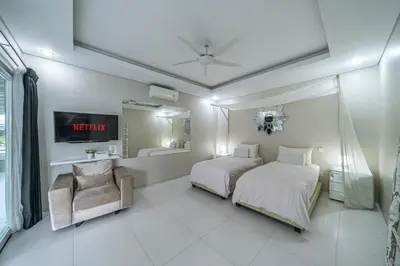a white bedroom with two beds and a chair at VILLA BALI OM CENTER - Best Location, Beautiful Villa Near the Beach in Canggu