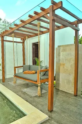 a swinging bed on a patio with a wooden pergola at Villa Casey in Seminyak