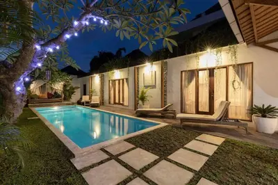 a swimming pool in front of a house at night at Elvano villa in heart of seminyak and near beach in Seminyak