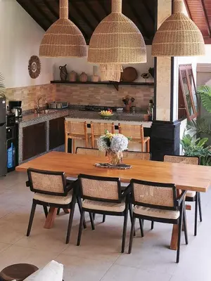 a large wooden table with chairs and a kitchen at Villa Casa Orana in Seminyak