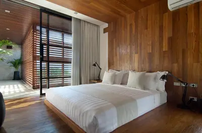 a bedroom with a large bed with a wooden wall at 4BR Villa Jumat - Minggu Villas Seminyak in Seminyak
