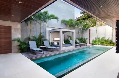 a swimming pool with chairs and a table next to a building at 4BR Villa Jumat - Minggu Villas Seminyak in Seminyak