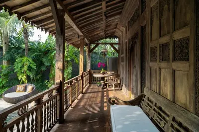 a wooden porch of a house with a table and chairs at Villa Kapungkur in Jimbaran