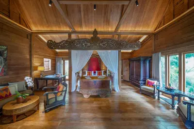 a bedroom with a bed in a room with wooden walls at Villa Kapungkur in Jimbaran
