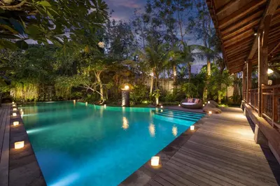 an infinity pool in a backyard with a wooden deck at Villa Kapungkur in Jimbaran
