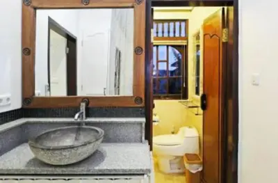 a bathroom with a large stone sink and a toilet at Blue Lagoon Apartment 3br in Kuta