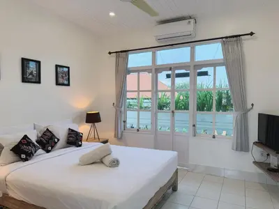 a bedroom with a bed and a large window at Beach House Apartment in Legian