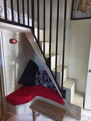 a red couch sitting under a stair case at Beach House Apartment in Legian