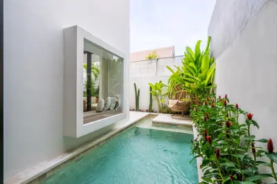 a swimming pool in the middle of a house with plants at Besso Villa by Betterplace in Canggu
