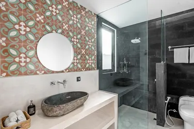 a bathroom with a stone sink and a mirror at Besso Villa by Betterplace in Canggu