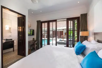 a bedroom with a bed and a desk and a bathroom at Villa Rua - Stylish luxury, tranquil location in Legian, walk to beach in Seminyak