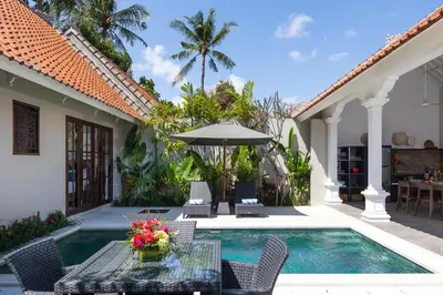 a patio with a table and chairs and a swimming pool at Villa Rua - Stylish luxury, tranquil location in Legian, walk to beach in Seminyak