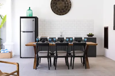 a kitchen with a table with chairs and a refrigerator at Villa Toru - Stylish luxury in Legian, tranquil location, walk to beach in Legian