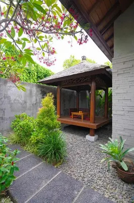 a gazebo with a bench in a garden at Bracha Villas Bali in Seminyak