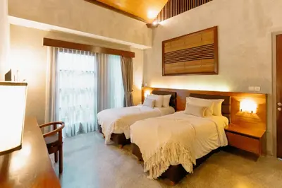 a hotel room with two beds and a window at Bracha Villas Bali in Seminyak
