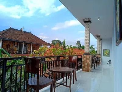a balcony with tables and chairs on a building at Roy Guest House in Canggu